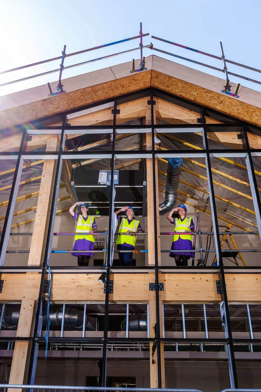 People in hi-vis jackets waving from building
