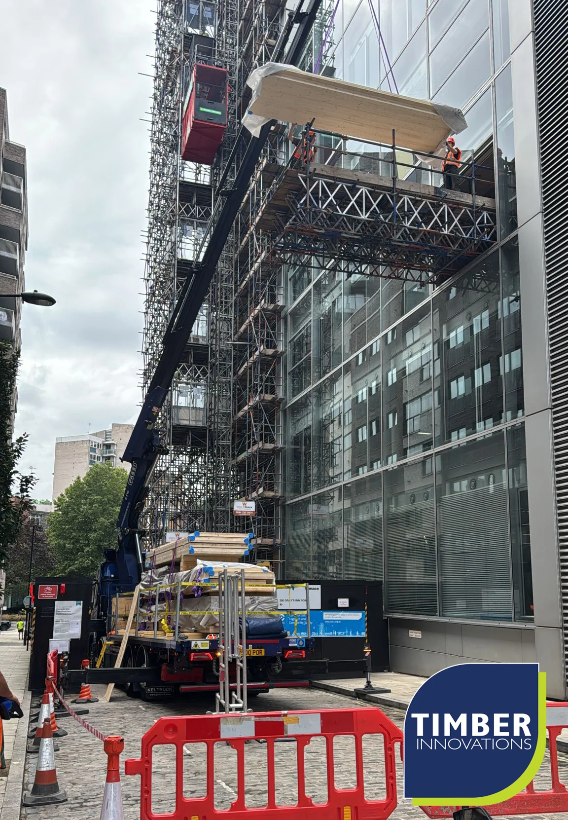 Crane lifting wooden panels by glass building