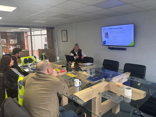 Attendees of the self build it workshop sat at the table facing the tv screen. 