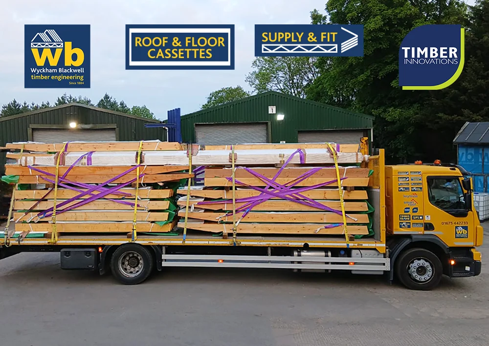 Roof Cassettes on WB Lorry1 08:05 copy Wyckham Blackwell flatbed lorry carrying stacked prefabricated timber roof cassettes secured with purple straps for delivery.