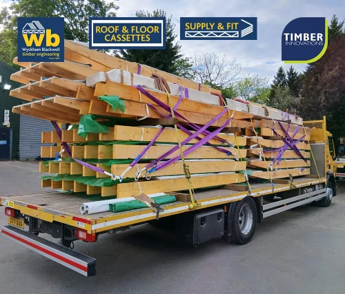Wyckham Blackwell flatbed lorry carrying stacked prefabricated timber roof cassettes secured with purple straps for delivery.